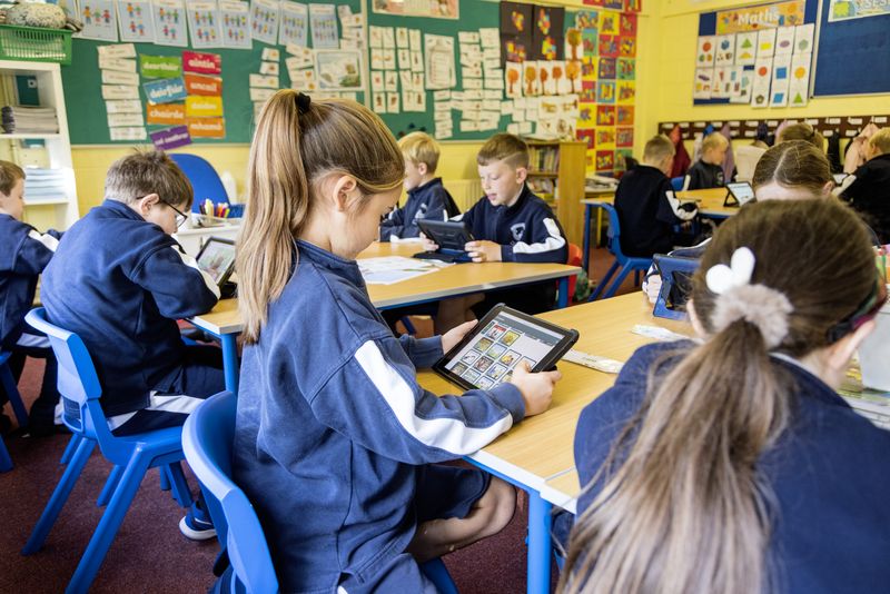 A class working on tablets around their tables