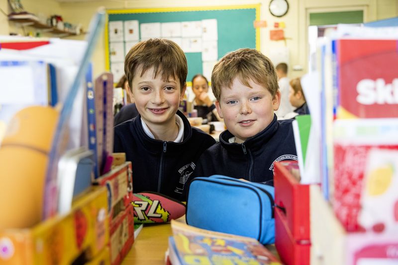 Two boys smiling behind their desk tidies