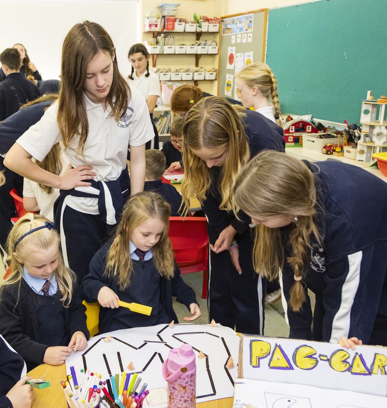 Older pupils helping younger ones make a board game