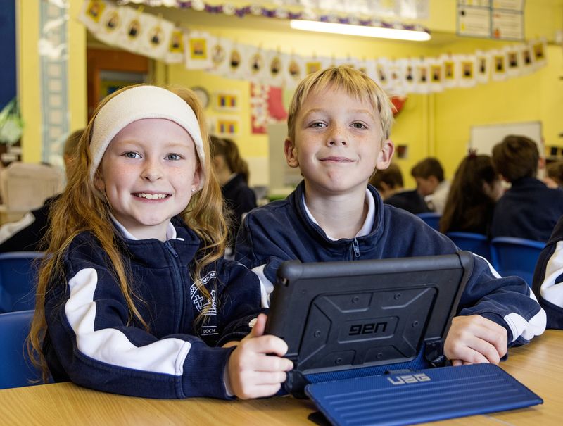 Two smiling pupils with their tablet