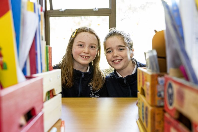 Two girls smiling by the classroom window